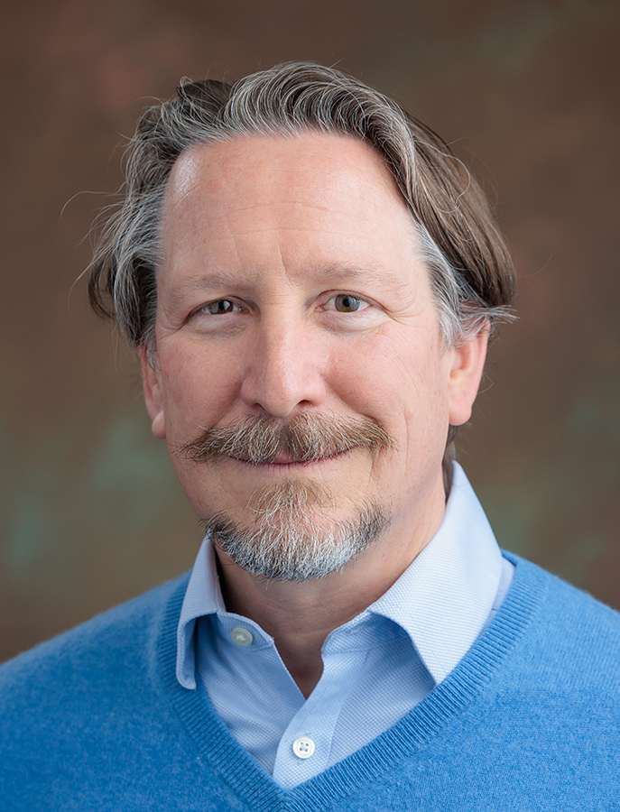 Aaron Pitluck smiling in a blue sweater