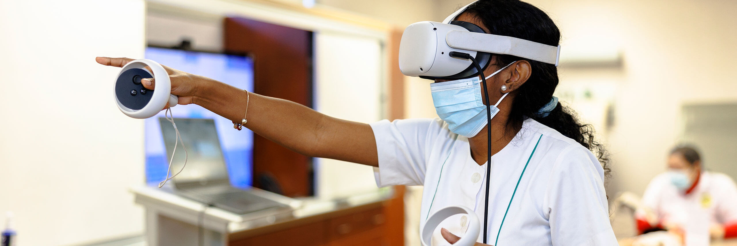 Person wearing a virtual reality headset and holding controllers in an indoor setting.