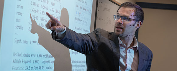 Instructor pointing out notes on a white board.